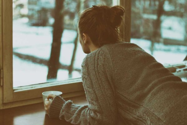 Woman deep in thought, staring out the window, contemplating the idea 'My ex wants to be friends